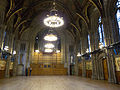 The Great Hall, Manchester Town Hall, is 50 feet wide and about 100 feet long, with Waterhouse's wooden roof with painted coats of arms, gasoliers and its lower walls decorated with Ford Madox Brown's The Manchester Murals