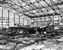 A damaged airplane in a destroyed hangar