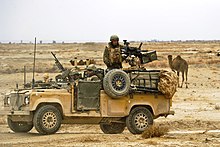 Desert-coloured Land Rover with mounted machine gun