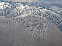 Aerial photo of the Great Sand Dunes partially surrounded by a mountains range with ridges and valleys