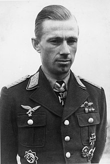 Black-and-white photograph showing the face and upper body of a young man in uniform. The front of his shirt collar bears Iron Cross decorations, black with light outline.