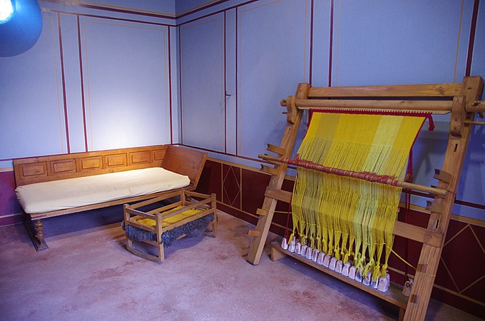 Reconstruction of a Roman loom. Warps have been chainstitched together; weights are resting on a low bench.