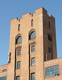 Close-up photo of Lafayette building tower. Visible are rooftop parapets arched windows with decorative corbels.