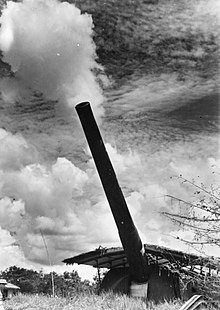 A large calibre gun fires, creating a cloud of smoke