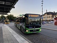 A green Uppsala city bus at the Uppsala central station, a yellow regional bus can be seen in the background.
