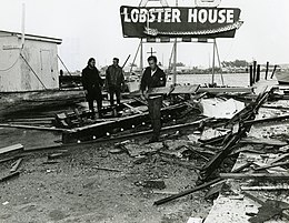 Mass of wooden wreckage with culinary advertisement in background