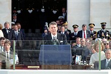 Reagan speaking at the podium with dignartaries behind