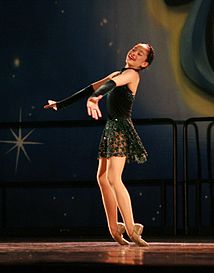 A dancer performs a "toe rise", in which she rises from a kneeling position to a standing position on the tops of her feet.