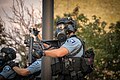 Polizist mit Atemschutzmaske beim Verschießen von Tränengasgranaten