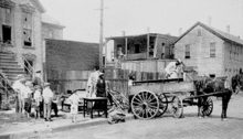 B&W photo of people loading things on a street