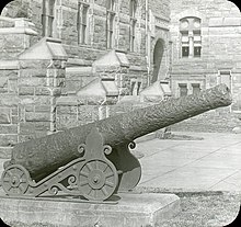 Photograph of a cannon in front of the steps at Healy Hall