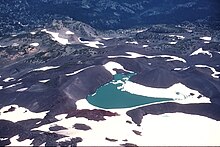 A snow-covered lake surrounded by dark glacial till
