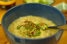 Golden yellow porridge garnished with scallions and fried bits