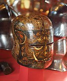 A painted knight's helmet depicting an intimidating mythical beast with large fangs.