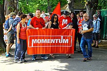 Group of Momentum supporters outdoors, holding a banner