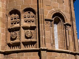 Flat striated pillars (one of which forms the axis of symmetry, separating two windows with semi-circular arches) and richly decorated blind windows in the apse of San Juan de Rabanera Church in Soria, Spain.