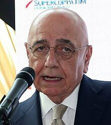 Adriano Galliani wearing a jacket and tie speaking into a microphone