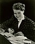 Promotional photograph of Kristina Söderbaum smiling to the front, her hands holding a pen