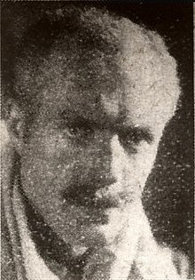 Newsprint photograph of a middle-aged man with a long face, short hair and moustache