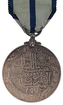 Rückseite der Delhi Durbar Medaille mit persischer Inschrift in einem Blumenkranz aus Rosen.