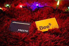 photograph of fare cards on a red fluffy carpet, with multicoloured fairy lights in the background. the mood is warm and dark. the cards are a black presto card, and a yellow bee card