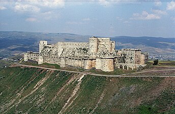 An enormous castle with encircling walls, on a rise in barren country with distant mountains.