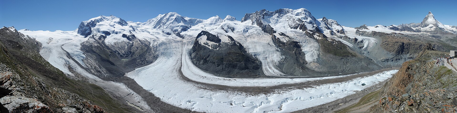 Panorama des Alpenhauptkamms südlich von Zermatt. Die Hauptgipfel und -grate, die sichtbar sind, sind (von links nach rechts): Weissgrat, Nordend und Dufourspitze (Monte-Rosa-Massiv), Liskamm, Castor, Pollux, Breithorn, Klein Matterhorn, Matterhorn. Die abgebildeten Gletscher sind (von links nach rechts): Gornergletscher (auch im unteren Bildteil), Monte-Rosa-Gletscher, Grenzgletscher, Schwärzegletscher, Breithorngletscher, Triftjigletscher, Unterer Theodulgletscher, Oberer Theodulgletscher