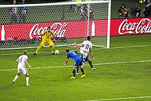View of Klose with the ball having just been kicked, with two Argentine defenders having contested the ball, while goalkeeper Romero awaits and another German player looks on
