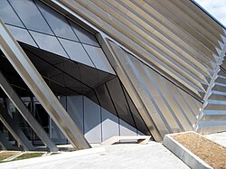 The entrance of the Eli and Edythe Broad Art Museum, highlighting the complex angles of the building and movement from the stainless steel pleated exterior and layered concrete arches.