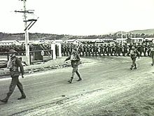 Soldiers march through the gates of a military barracks