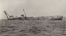 A large warship rolls onto its side.
