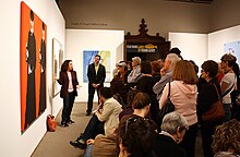 A group of people watching a presentation in a gallery