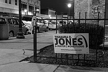Black-and-white photograph of a yard sign promoting Jones's 2017 mayoral campaign, reading "Tishaura O. Jones for Mayor #OneStLouis"