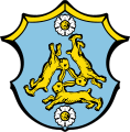 Gemeinde Hasloch In Blau drei mit den Ohren zusammenhängende, im Dreieck angeordnete goldene Hasen; oben und unten je eine silberne Rose mit goldenen Butzen.