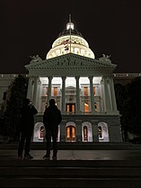 California State Capital at night with flags at half mast