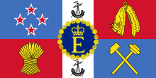 A flag featuring the shield design of the New Zealand coat of arms in the form of an oblong. Superimposed in the centre is a blue roundel bearing a letter 'E' surmounted by a crown within a garland of roses all in gold.