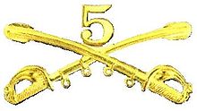 A computer generated reproduction of the insignia of the Union Army 5th Regiment cavalry. The insignia is displayed in gold and consists of two sheafed swords crossing over each other at a 45 degree angle pointing upwards with a Roman numeral 5