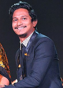 Azim receiving an award trophy with a smaile