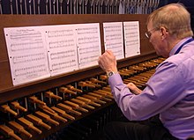A man plays a carillon's wooden keyboard with his fists.