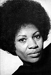 Toni Morrison is pictured in a turtle-neck. She is sporting an afro.