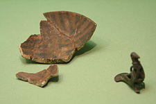 Bowl (clay, painted green and yellow) and bird-shaped pendant (bronze)