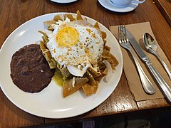 Chilaquiles may be served with minimal salsa applied at the last minute to preserve the crispiness of the tortilla chips