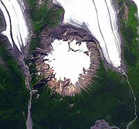 An overhead view of a circular, ice-capped mountain with two southerly-flowing glaciers to the northwest and northeast.