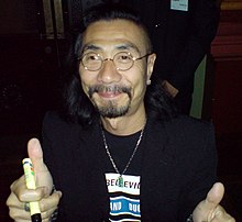 A middle-aged Japanese man smiling towards the camera.