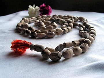 Hindu Japa mala prayer beads, made from Tulasi wood, with the head bead in the foreground.