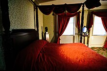 A bedroom, which belonged to Aaron Burr, with a red bedspread