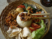 Personal serving of Nasi Bali, in Indonesia, rice surrounded by numbers of side dishes including sate lilit.
