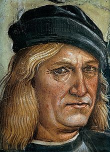 Middle aged or old man with long blond hair and black hat