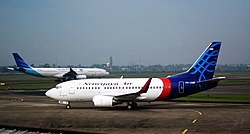A Sriwijaya Air Boeing 737-500 at Soekarno Hatta Airport with a Garuda Indonesia Airbus A330-300 in the background.