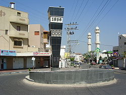 Roundabout in Kafr Qasim with a monument for the massacre in 1956, the central mosque with another monument, and mixed-used buildings.